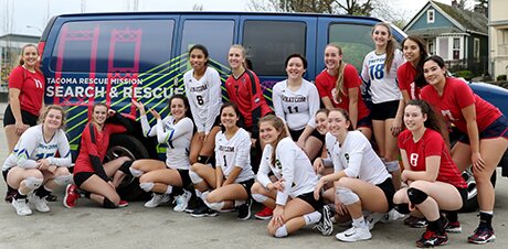 NWAC Volleyball Players huddled around the Tacoma Rescue Mission van